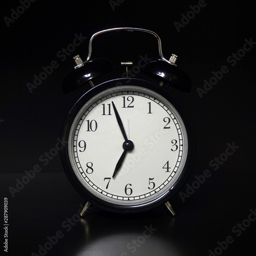 Classic mechanical alarm clock on dark background. Low key