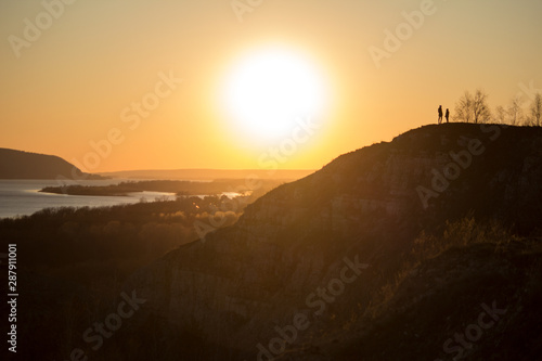 Couple meets sunset over the river standing on the mountain