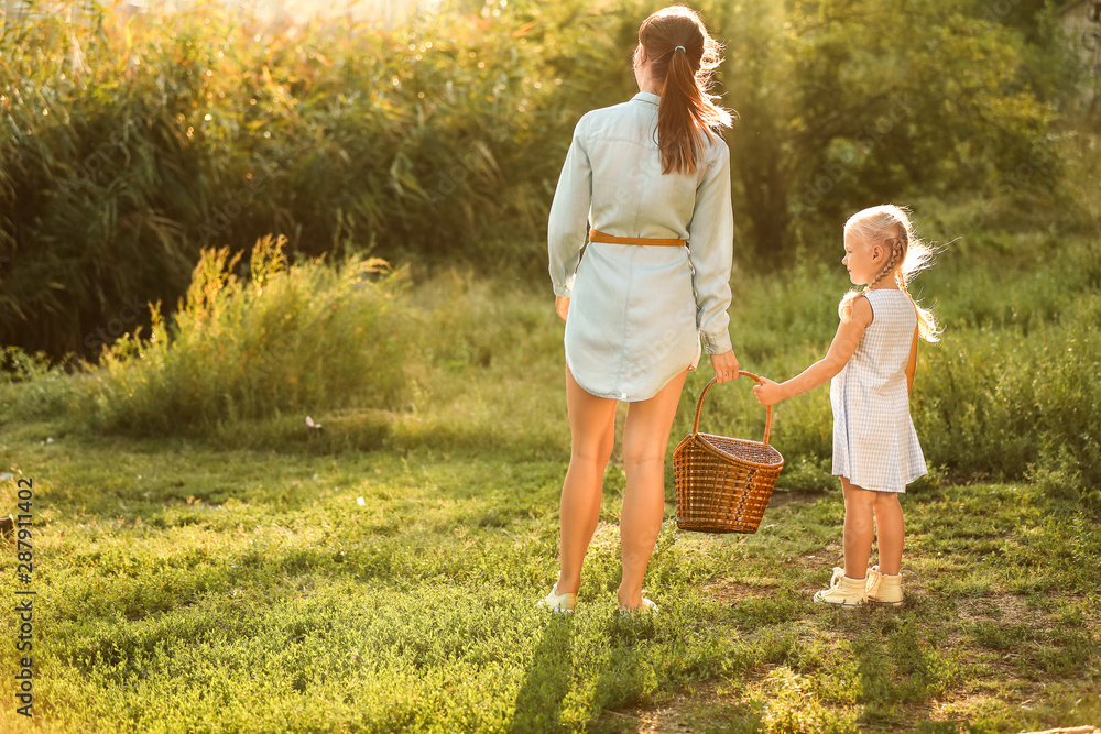 Happy mother and daughter with basket outdoors Happy mother and daughter with basket outdoors