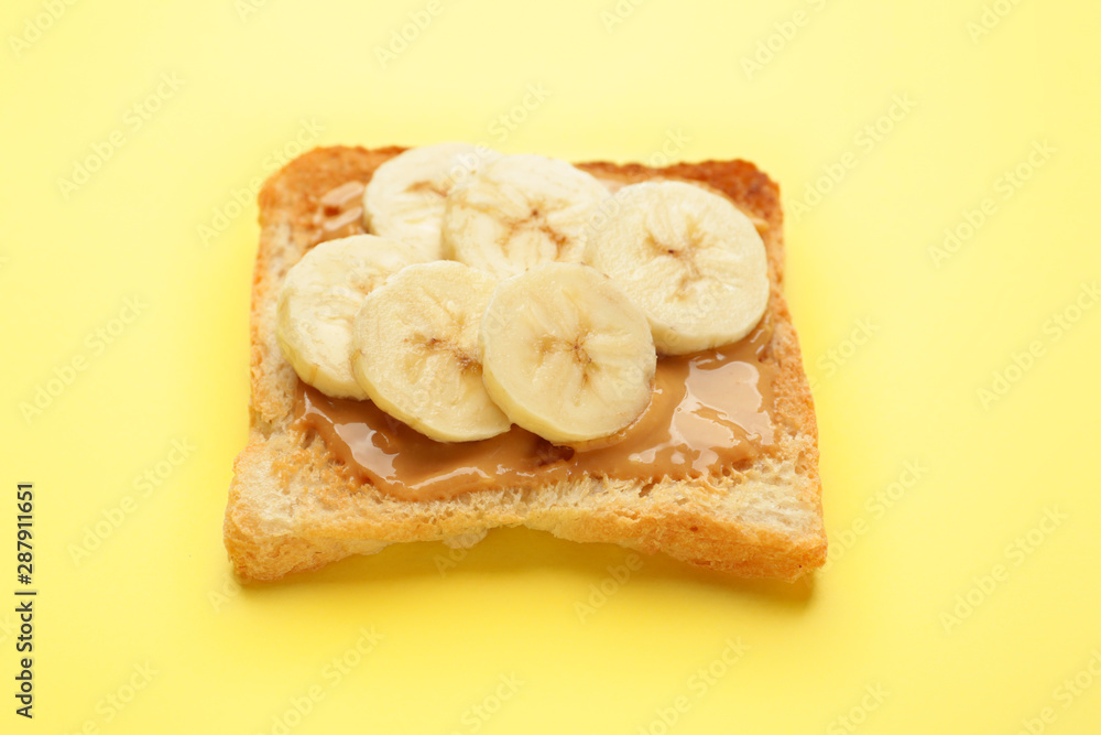 Tasty toasted bread with banana and peanut butter on color background Tasty toasted bread with banana and peanut butter on color background