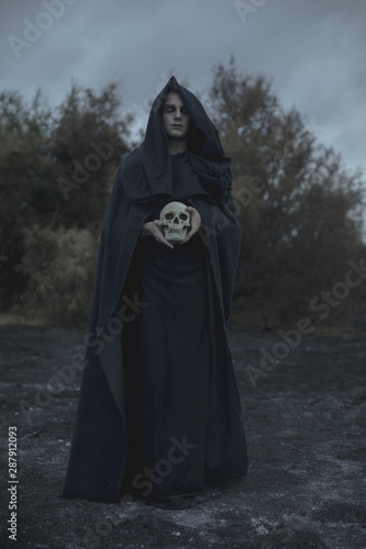 Long portrait of a man dressed as dark mage with skull