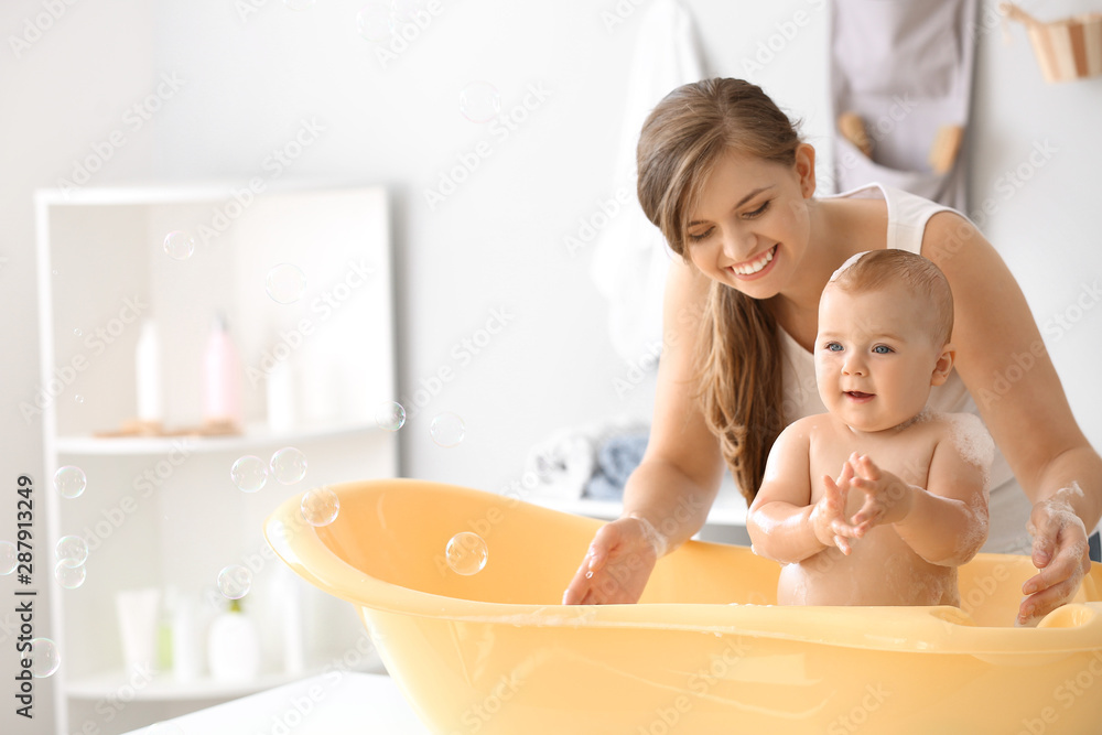 Mother bathing her cute little baby at home - obrazy, fototapety, plakaty 