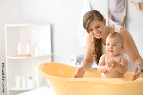 Mother bathing her cute lit...