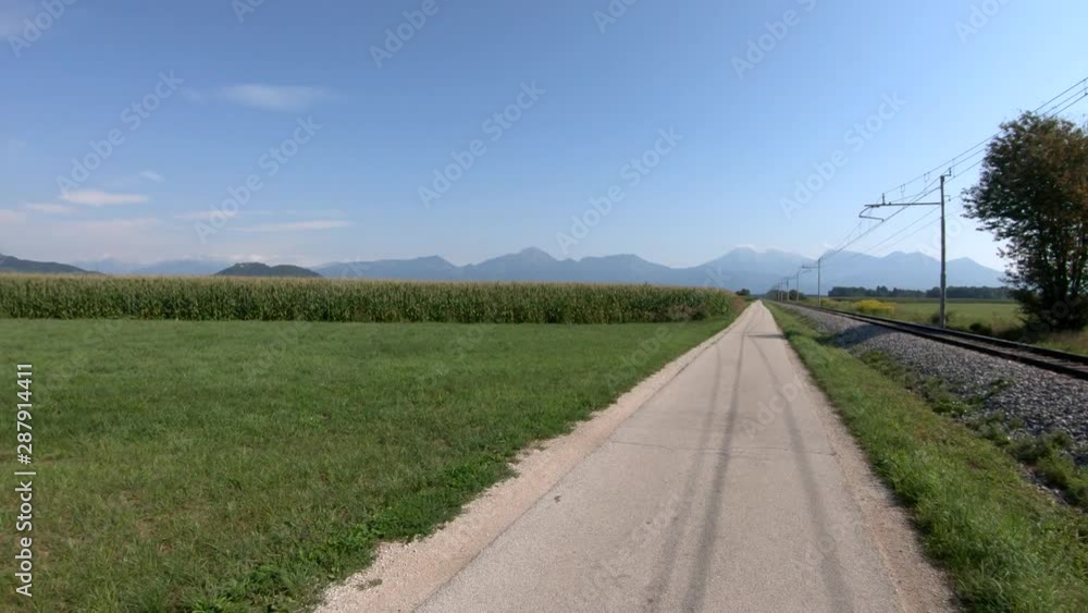 4K Forward moving left pan view train tracks near countryside road on bright day 4K Forward moving left pan view train tracks near countryside road on bright day