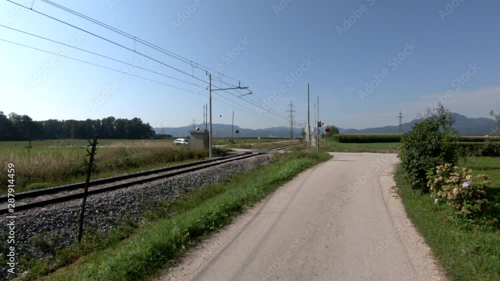 4K Forward moving left pan view train tracks near countryside road on bright day 4K Forward moving left pan view train tracks near countryside road on bright day