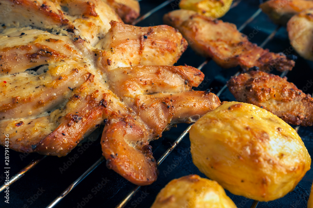 Grilled Chicken Breast with Slices Made for Marinade to Penetrate the Meat Better, and Ensure Chicken Cooked Evenly. Roasted Potatoes and Chicken Slices on Stainless Steel Cooking Grid.