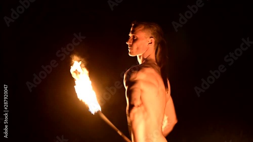 Fire show. Man juggles with two burning torches. Night show. Mastery of the fakir. Close-up photo