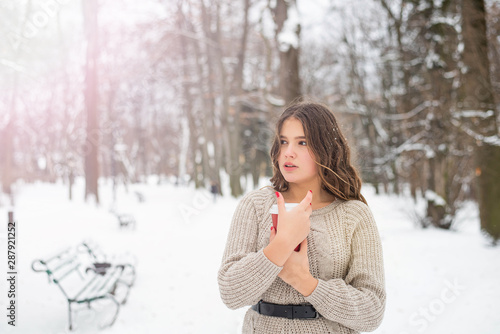 Beautiful smiling cute teenage girl with natural make up and long hairl holds a cup with hot coffee or tea. Winter season. photo