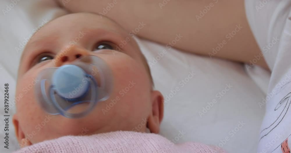 Newborn Baby Lying in Bed Sucking on a Pacifier Newborn Baby Lying in Bed Sucking on a Pacifier