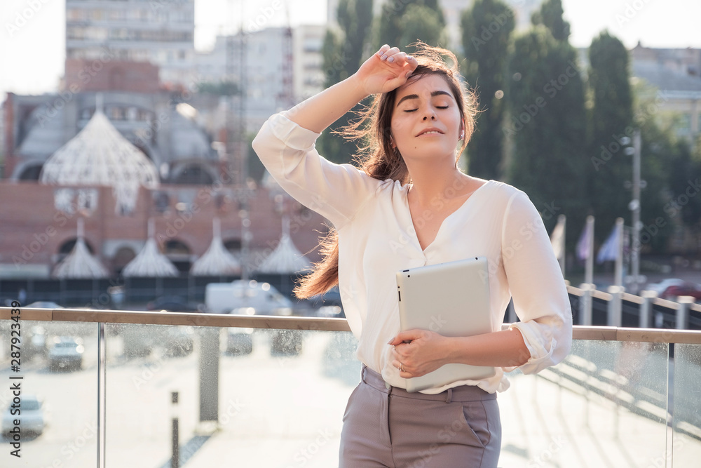 Young brunette business woman in white skirt and grey suit trousers chilling, relaxing after hard day at work. European city on background. copy space