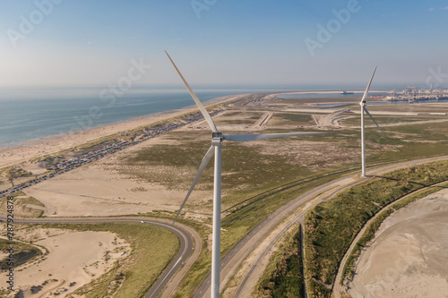 Huge wind turbine on the beach of Maasvlakte II, Rotterdam. With a road and carpark behind the dunes of the recreational beach Maasvlaktestrand.  The North Sea and container terminals with harbor photo