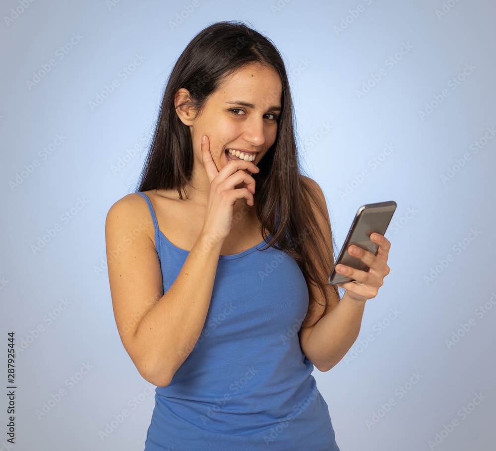 Attractive young woman looking at mobile smart phone shocked and surprised having lost of likes Attractive young woman looking at mobile smart phone shocked and surprised having lost of likes
