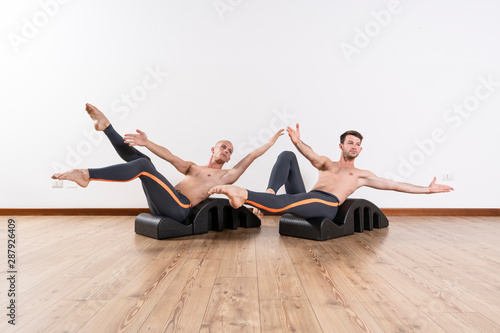 Male couple praticing Pilates exercises