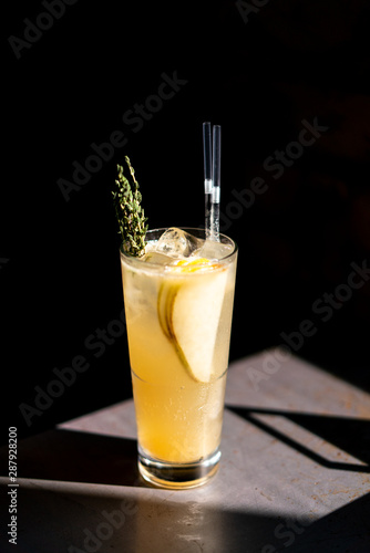 A glass of pear lemonade on an iron table with amazing light and deep black background.