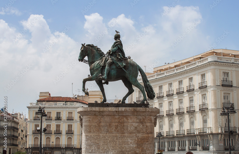 The Gateway of the Sun Square (Puerta del Sol) and the Statue of King Charles III in Madrid, Spain. This is the centre (Km 0) of the radial network of Spanish roads and and busiest place in the city. The Gateway of the Sun Square (Puerta del Sol) and the Statue of King Charles III in Madrid, Spain. This is the centre (Km 0) of the radial network of Spanish roads and and busiest place in the city.