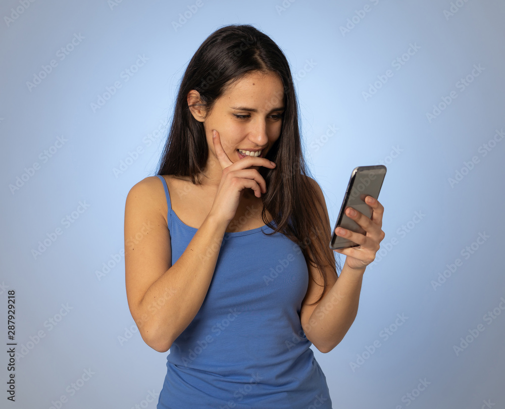 Attractive young woman looking at mobile smart phone shocked and surprised having lost of likes Attractive young woman looking at mobile smart phone shocked and surprised having lost of likes