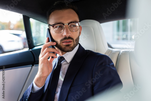Businessman calling his business partner while sitting in car © zinkevych