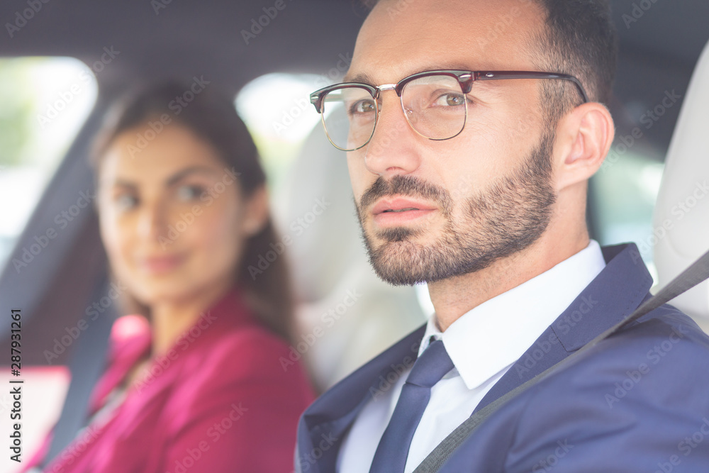 Bearded young man wearing glasses sitting near wife in car - obrazy, fototapety, plakaty 