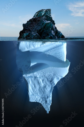 Iceberg floating in the ocean, both the tip and the submerged parts are visible. Top part is smaller than bottom.
