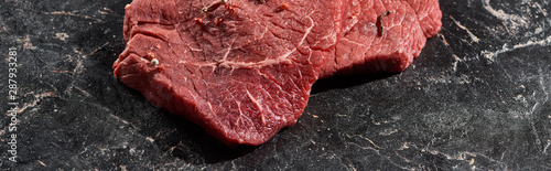 panoramic shot of fresh uncooked beef sirloin on black marble surface
