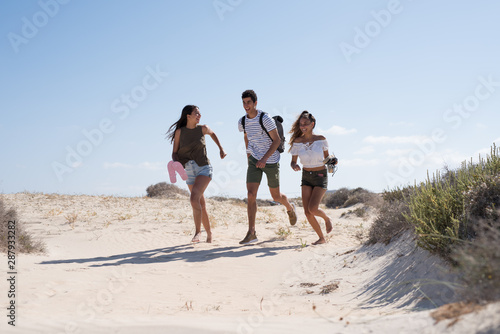 Three young people running on the beach