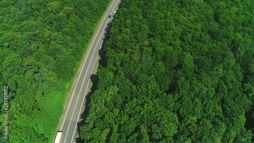 4K road between fields and forest belt. Cars overtaking each other on the road. photo