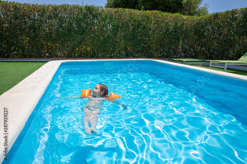 Canvas-taulu relaxed four years old blonde child with orange floater sleeves in arms, armband