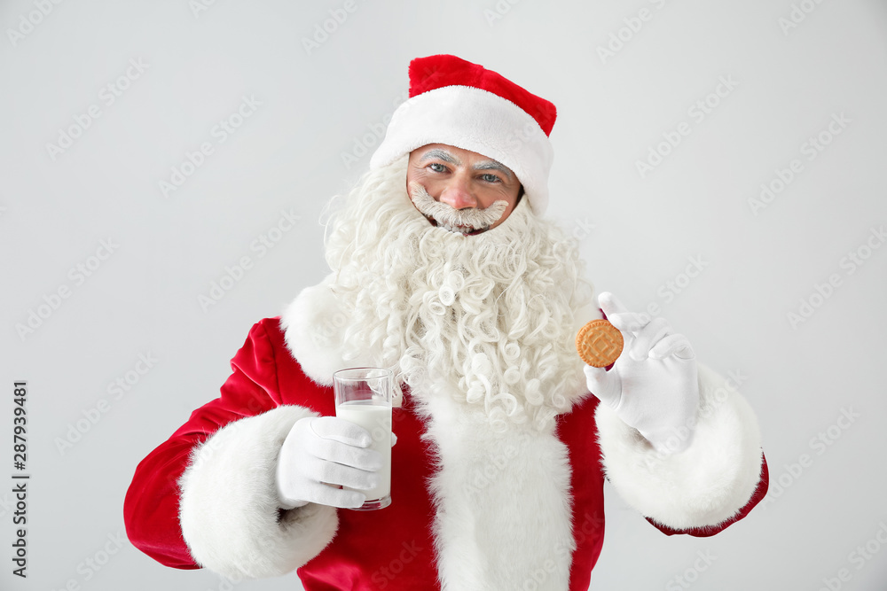 Portrait of Santa Claus with milk and cookie on light background