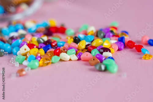 Multicolored beads for needlework on a pink background