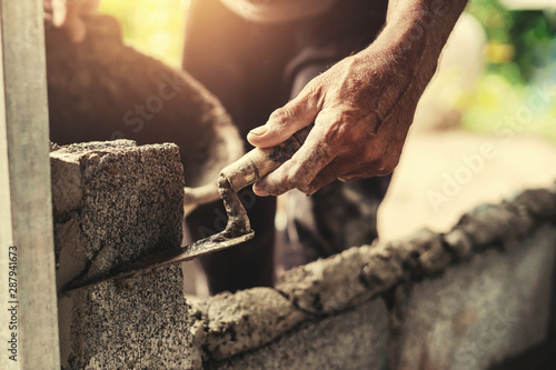 Foto hand of worker plastering cement on brick wall at construction site