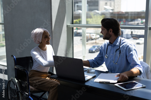 Disabled mixed-race woman shaking hands with Caucasian male doctor