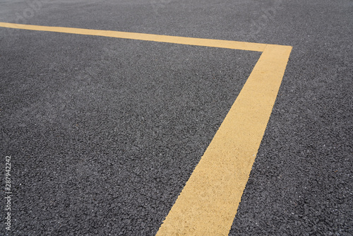 Low angle view of right angle yellow paint line on black asphalt road