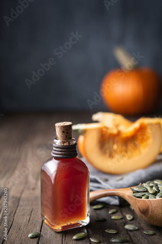 Cold pressed Pumpkin seed oil in a glass bottle, decorated with peeled seeds with copy space