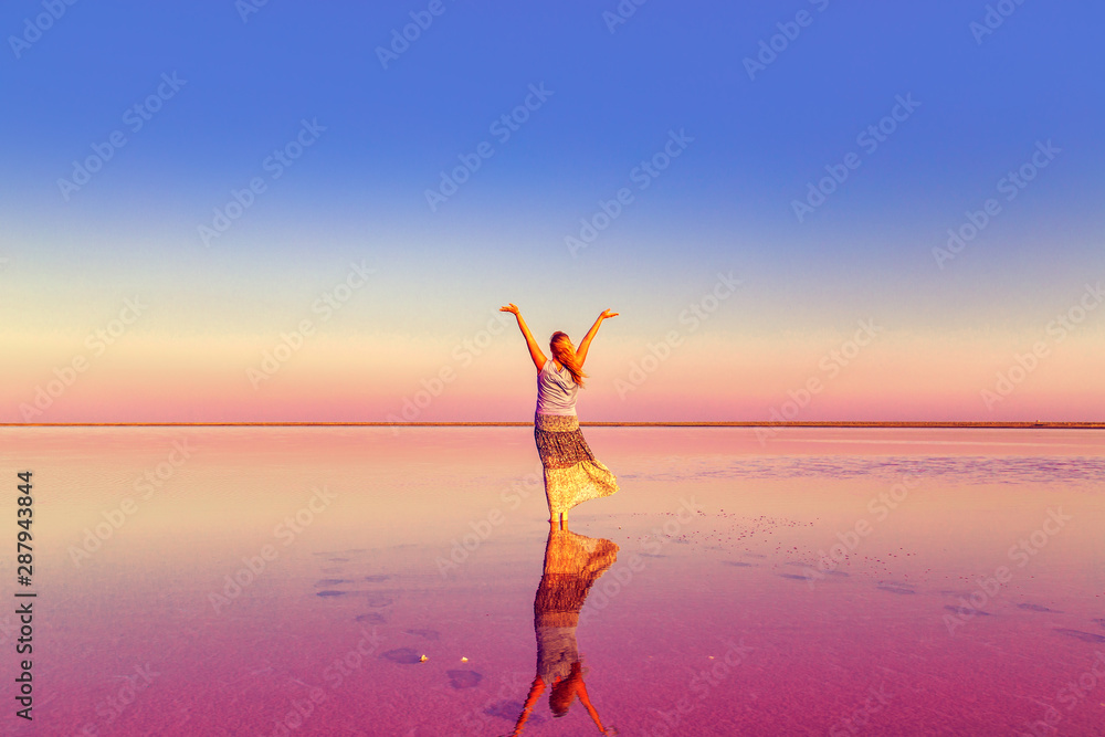 The girl in the pink lake. Unreal landscape at sunset.