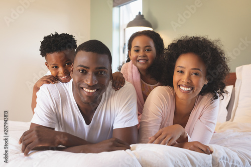 Happy African American family lying on bed and looking at camera
