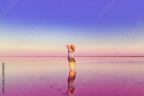 The girl in the pink lake. Unreal landscape at sunset.
