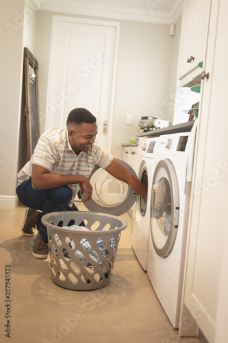 African American man washing clothes in washing machine