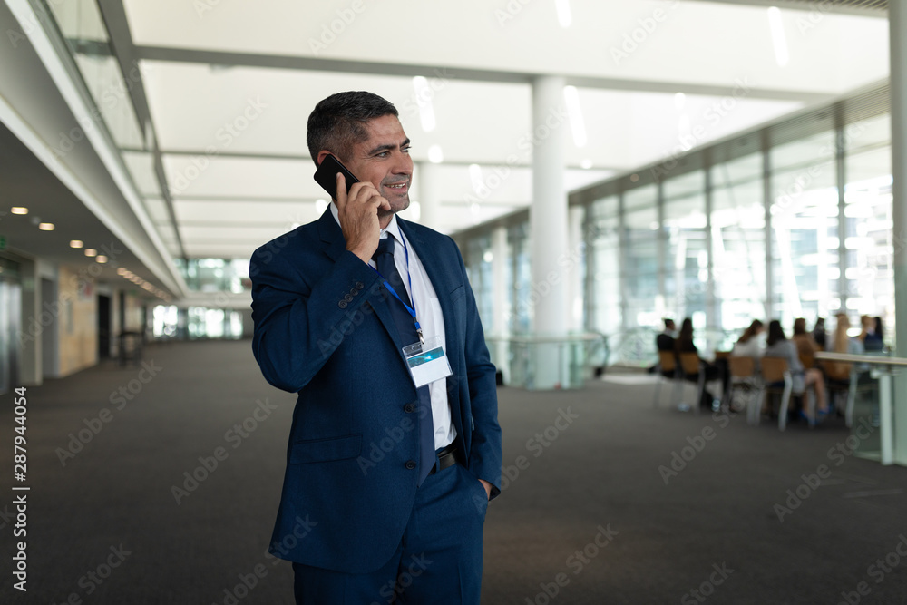 Businessman calling someone on mobile phone and looking away in office lobby Businessman calling someone on mobile phone and looking away in office lobby