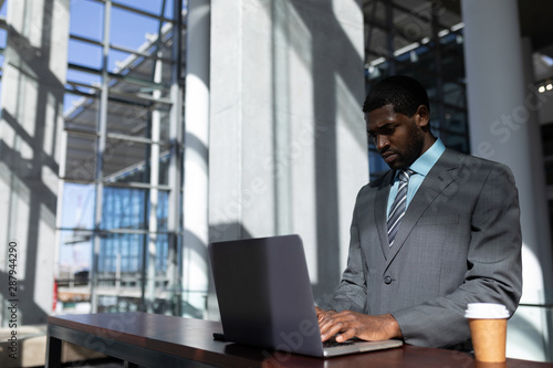 African-American businessman with coffee cup using laptop in office