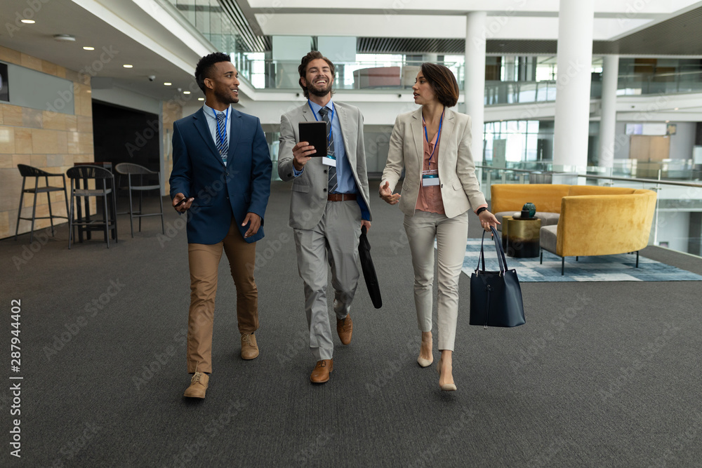 Multi-ethnic business people interacting with each other while walking on office floor