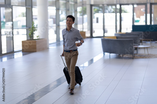 Asian male executive walking with luggage in the lobby