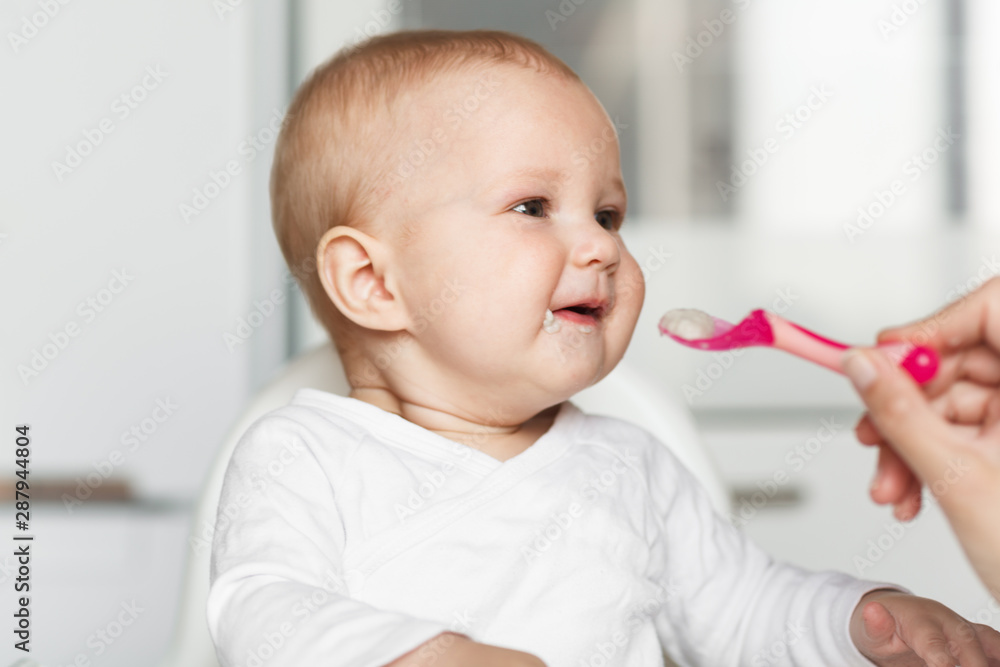 Feeding of cute baby with a spoon in the kitchen Feeding of cute baby with a spoon in the kitchen