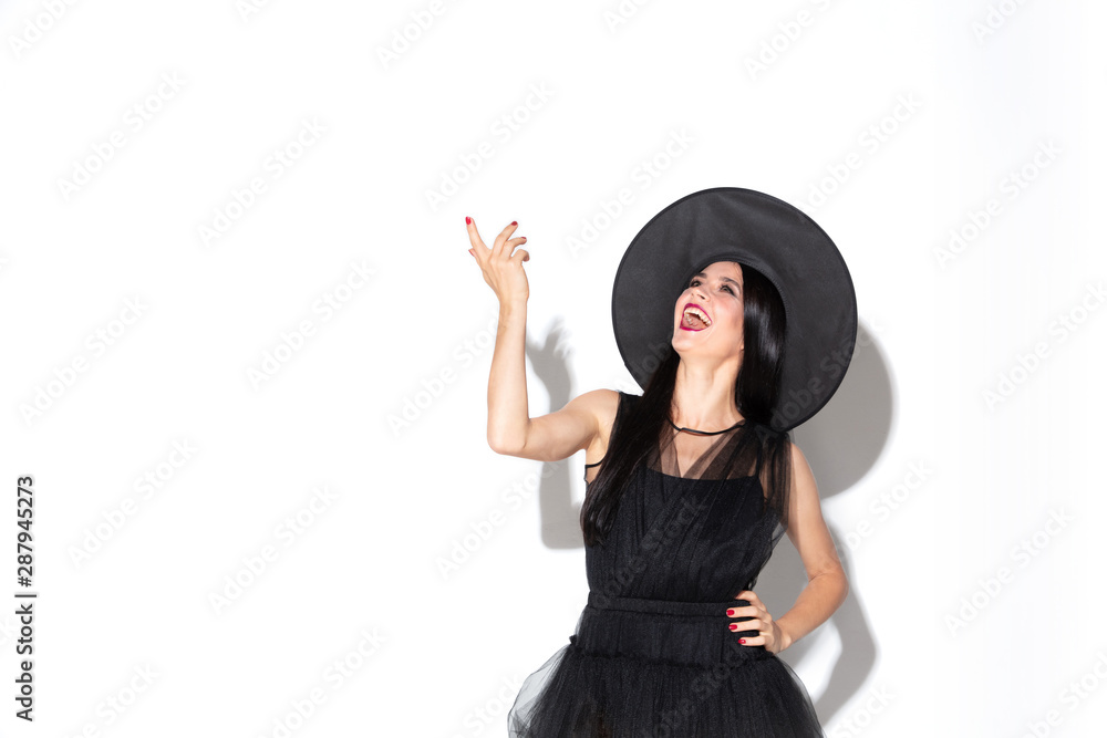 Young brunette woman in black hat and costume on white background. Attractive caucasian female model. Halloween, black friday, cyber monday, sales, autumn concept. Crazy happy and screaming. Young brunette woman in black hat and costume on white background. Attractive caucasian female model. Halloween, black friday, cyber monday, sales, autumn concept. Crazy happy and screaming.