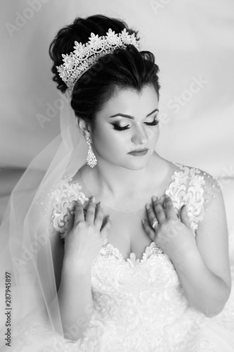 Young gorgeous bride is sitting in couch. Trendy wedding style shot. Young attractive a bride tender looking. Bride in beautiful dress sitting in home. Wedding. Sexy bride.  Black and white.