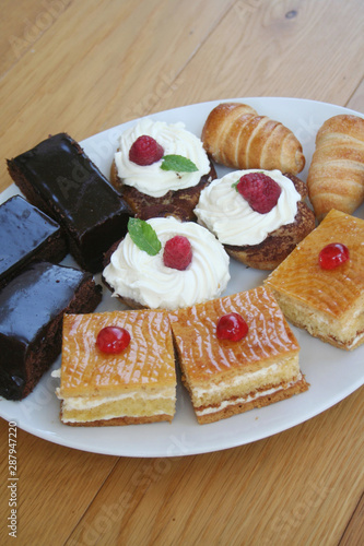Different pastry with chocolat and cream on a white plate on wooden table. Sweet food