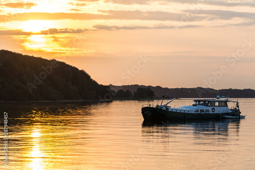 Boat anchoring just off the coast of the Baltic Sea during a beautiful colorful sunset photo