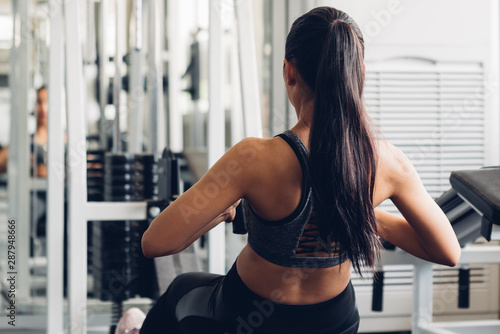 Attractive young sports asian woman lifting weight in gym.