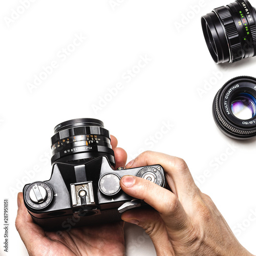 Stary, analogowy aparat fotograficzny i obiektywy na białym tle. Fotografowanie z ręki.