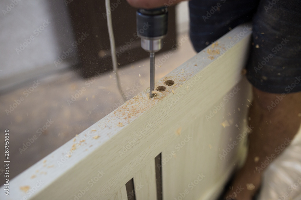 Drilling a hole in the furniture to install a lock on the door close-up.