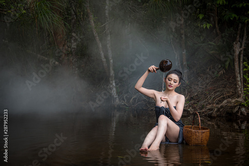 The sexy women white skin are bathing in a stream in a forest surrounded by trees. She enjoys rural life.
